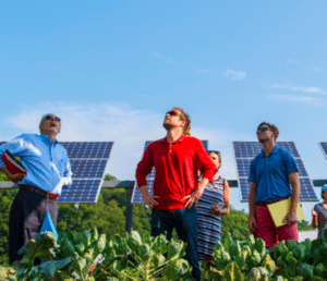 Three people stand In front of solar panels