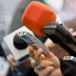 Microphones being held by journalists at a press conference outside